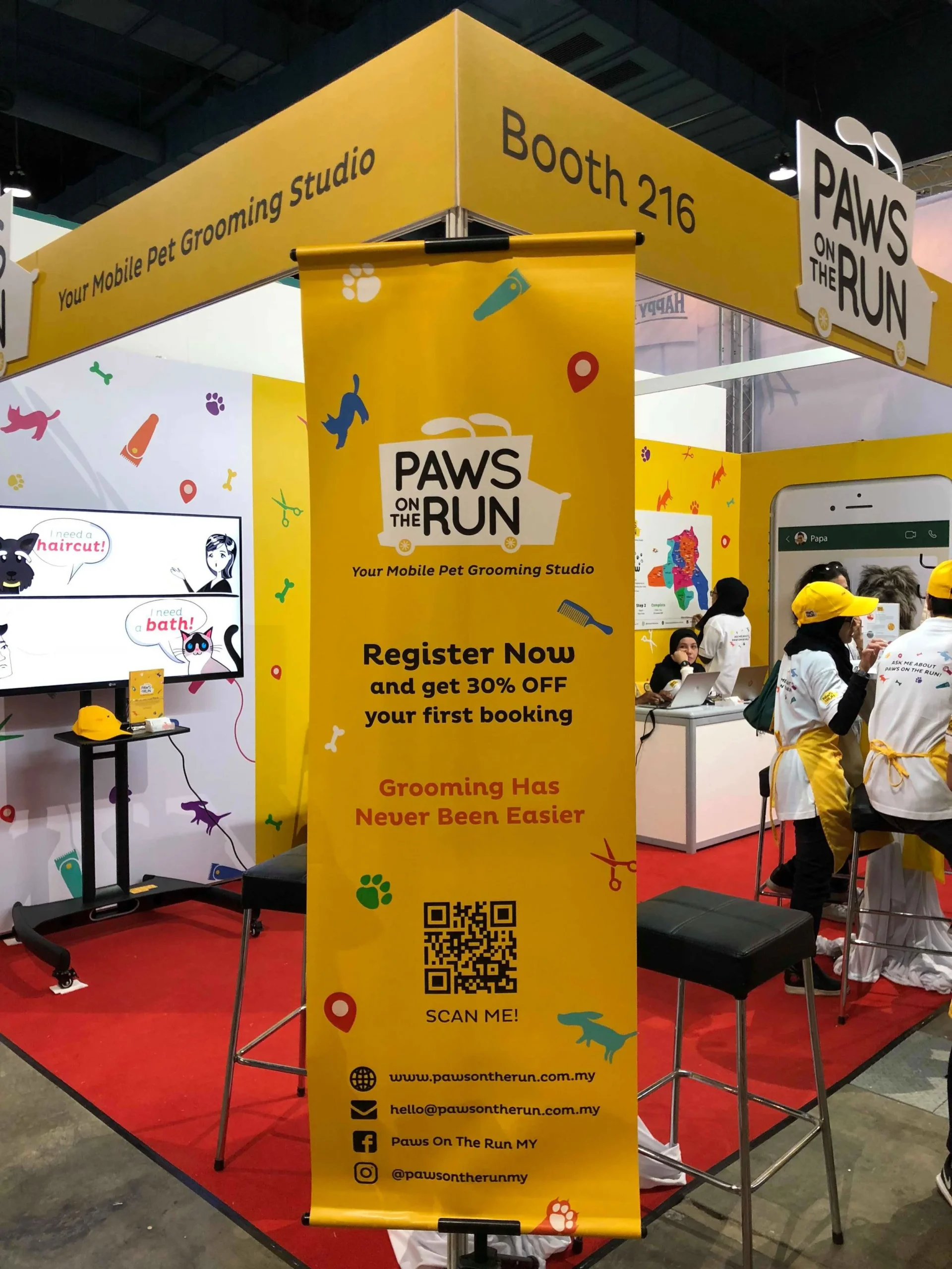A yellow vertical roll-up banner at the corner of the Paws On The Run booth