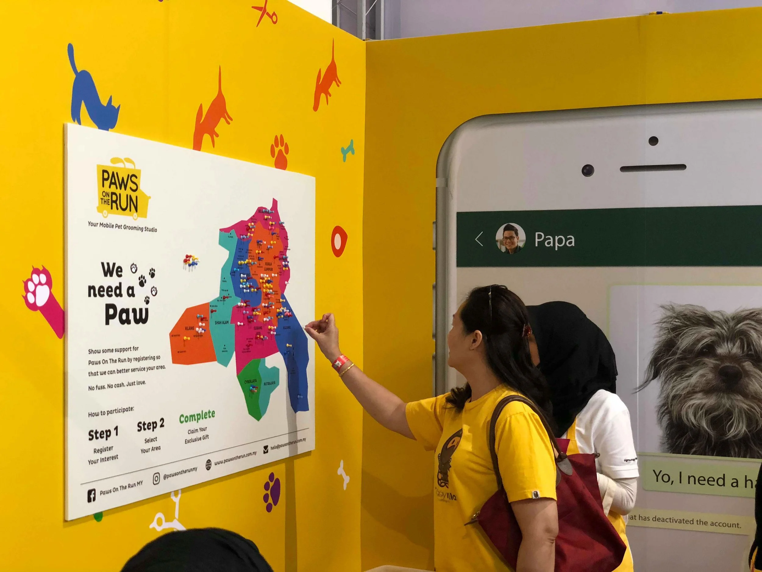 Two women placing a pin on the interactive physical map at the Paws On The Run booth