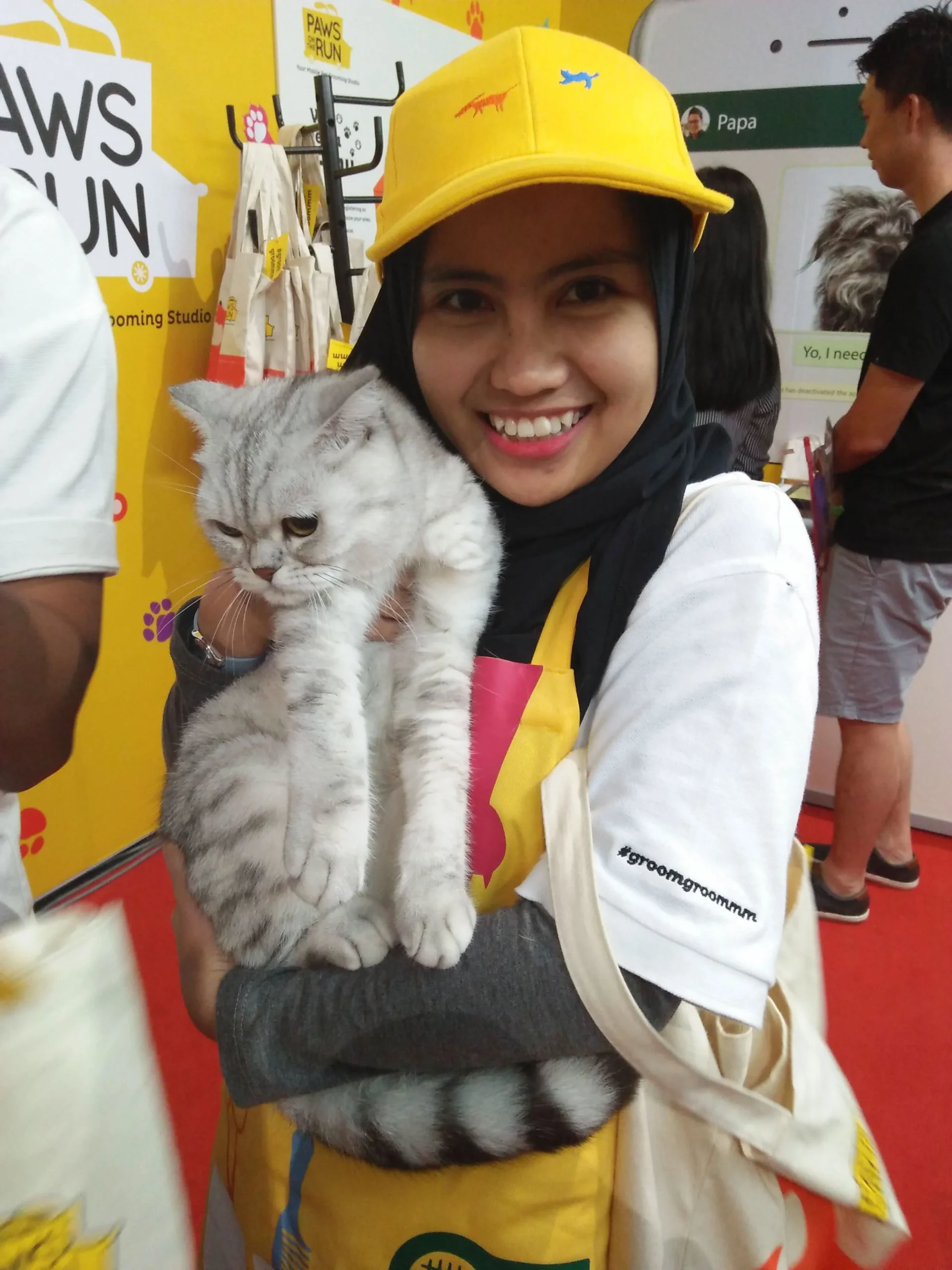 A young woman wearing a hijab holding up a Paws On The Run promotional flyer